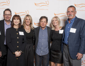 Board Members from the Danville d'Elegance (DDE) Foundation -- Tom Halloran, Brian Stephenson, Robin Halloran, Cadi Stephenson and co-founders Chris & Jim Edlund -- surround Michael J. Fox (center) after earning recognition as 'Top Fundraiser Nationwide' for Team Fox, the grassroots fundraising arm of the Michael J. Fox Foundation. DDE, celebrating its 10th anniversary in 2014, has raised more than $2mm for Parkinson's research and patient care over the past decade.